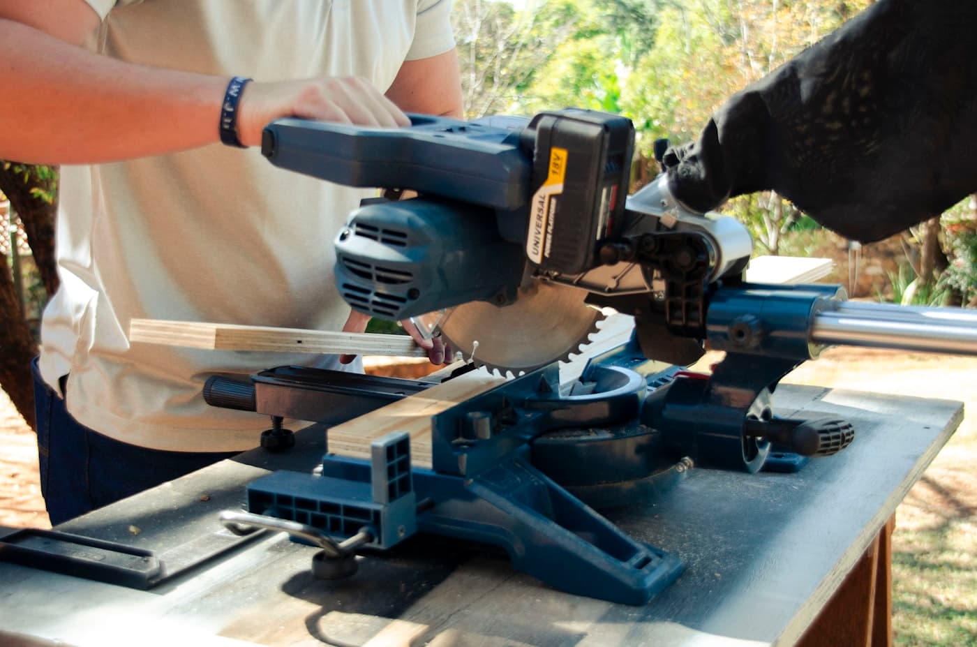A carpenter making a cut on a mitre saw